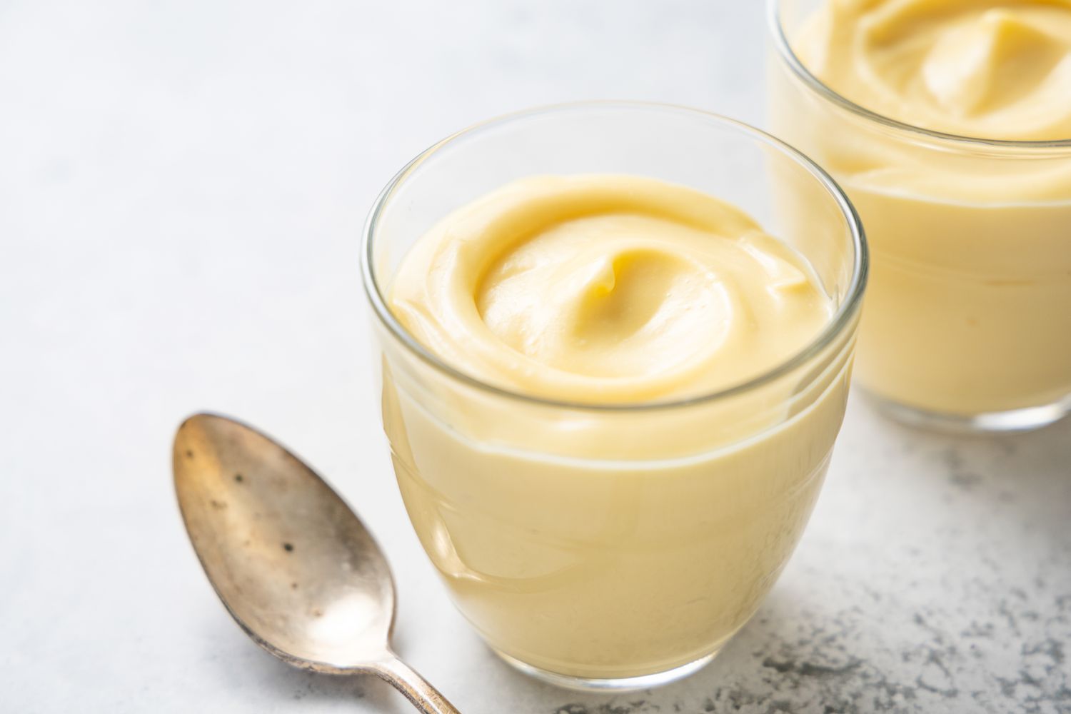 Vanilla Custard in Pudding Jars Next to a Spoon