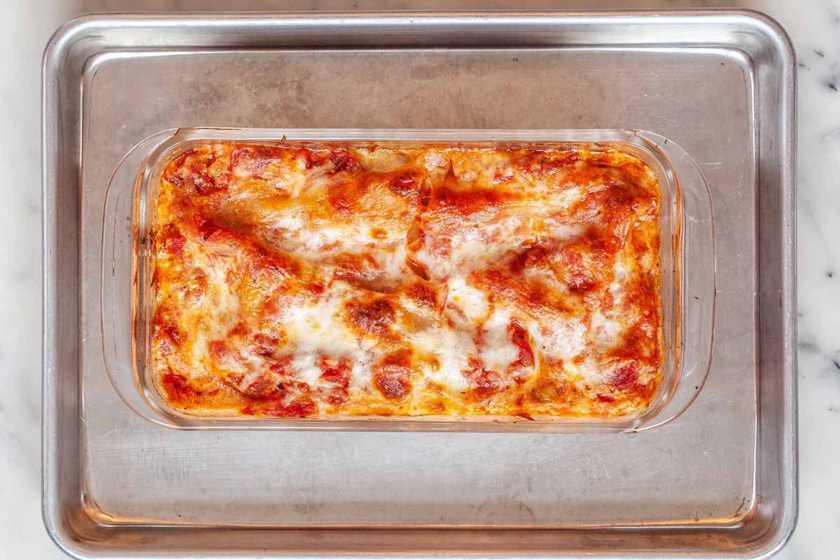 Overhead view of small batch lasagna baked in a glass loaf pan and sitting on a baking sheet.