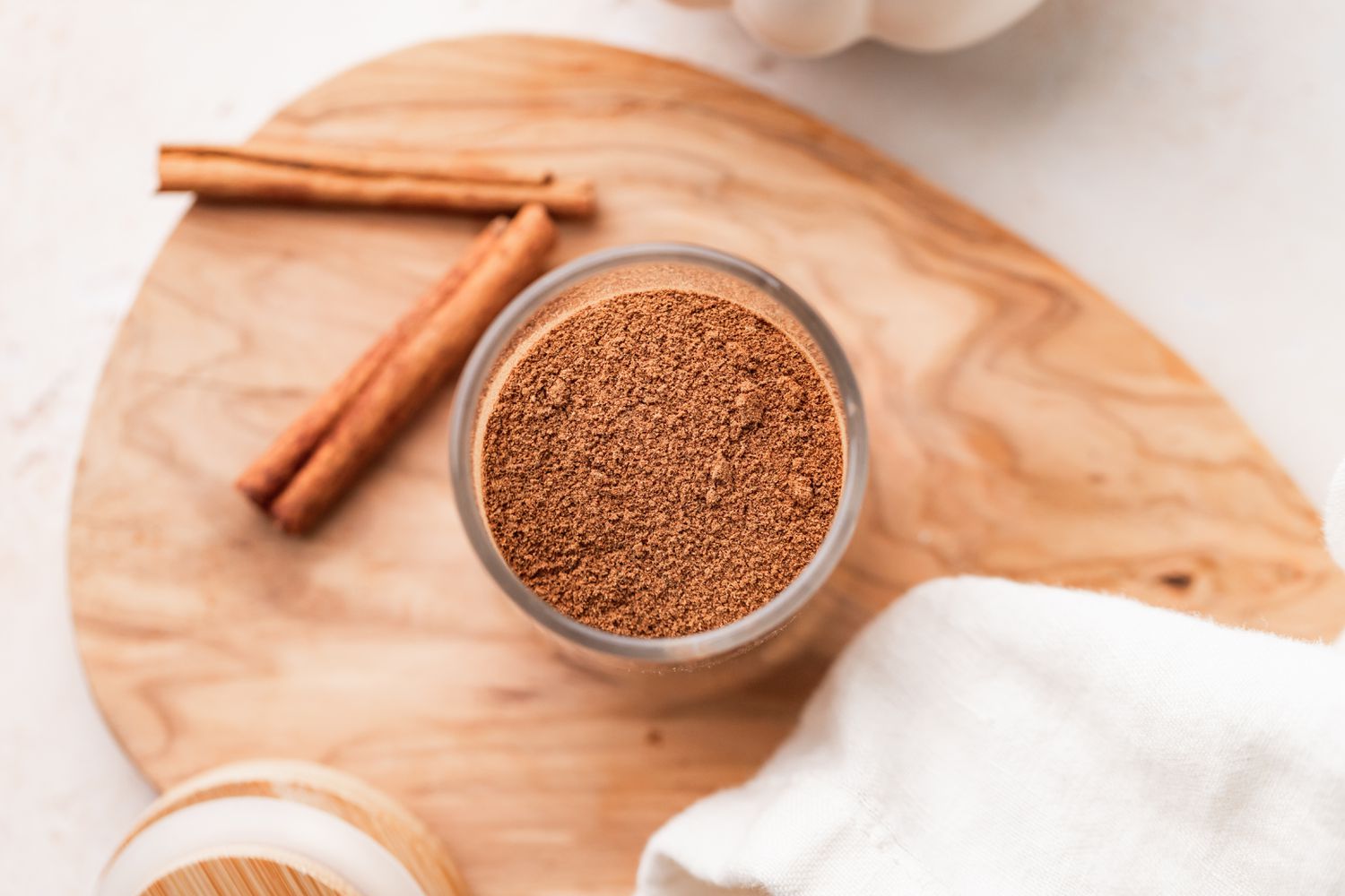 Overhead view of DIY pumpkin spice blend on a wooden cutting board with cinnamon sticks next to it.