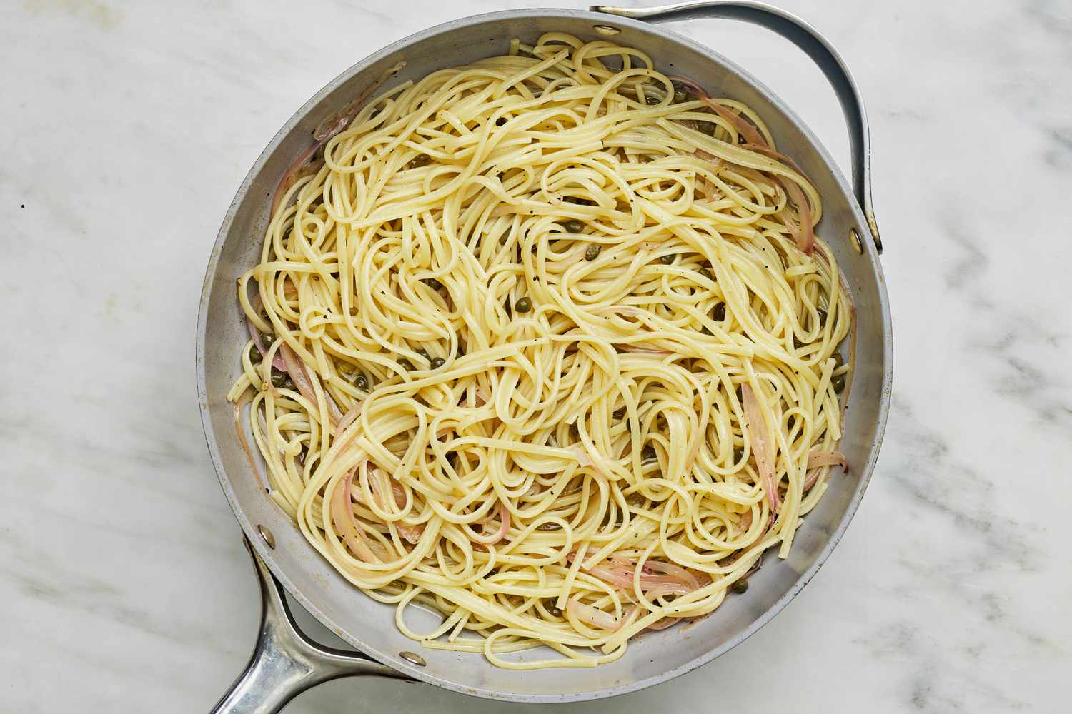 Pasta added to pan with the sauce ingredients for pasta with tuna and capers recipe