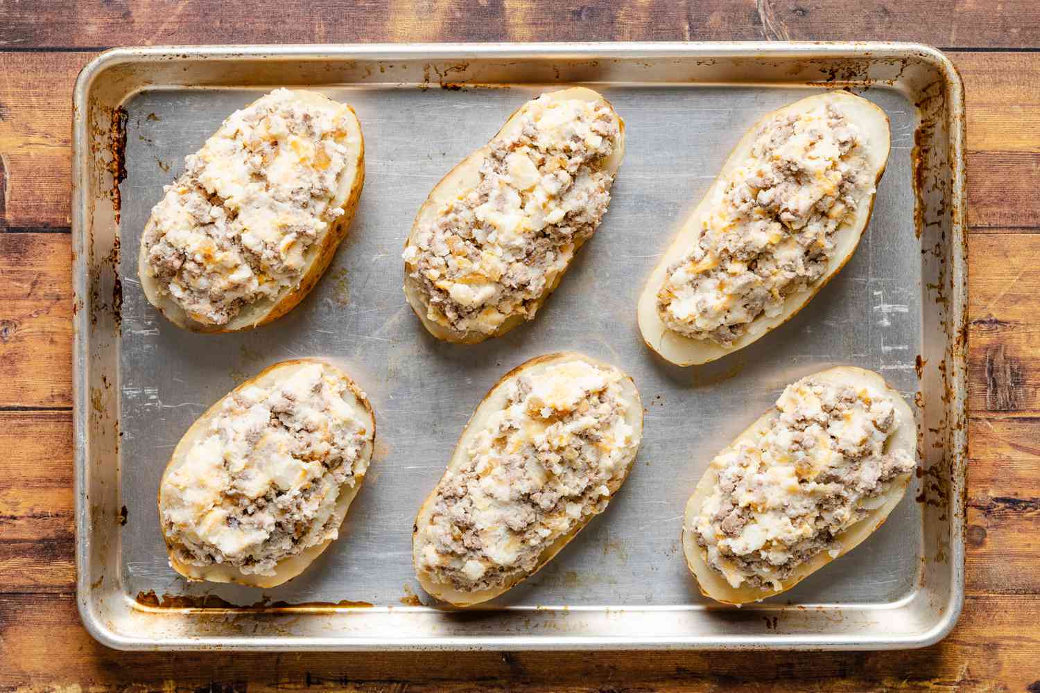 filling added to baked potato shells on the baking sheet for cheeseburger stuffed baked potatoes recipe