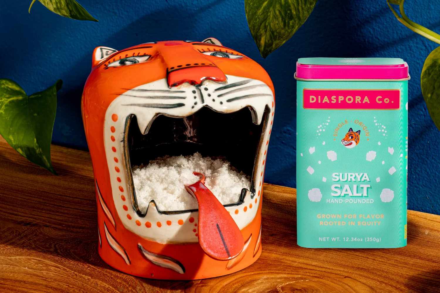 A tigershaped salt holder filled with salt placed next to a pack of Surya Salt by Diaspora Co