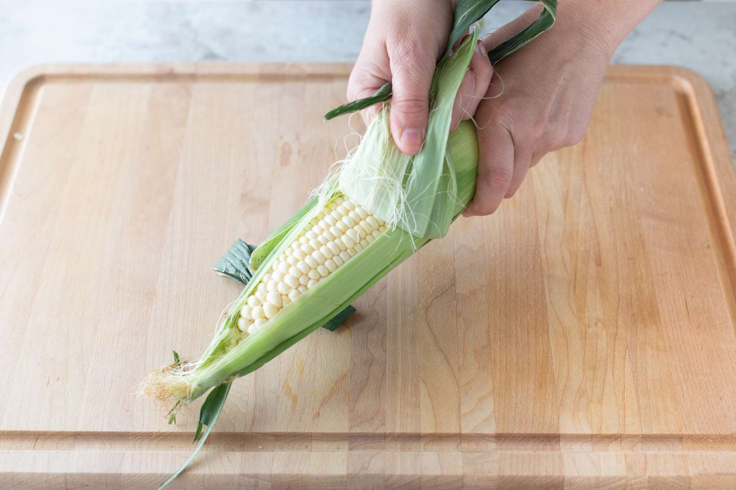 Pulling the husk off an ear of corn