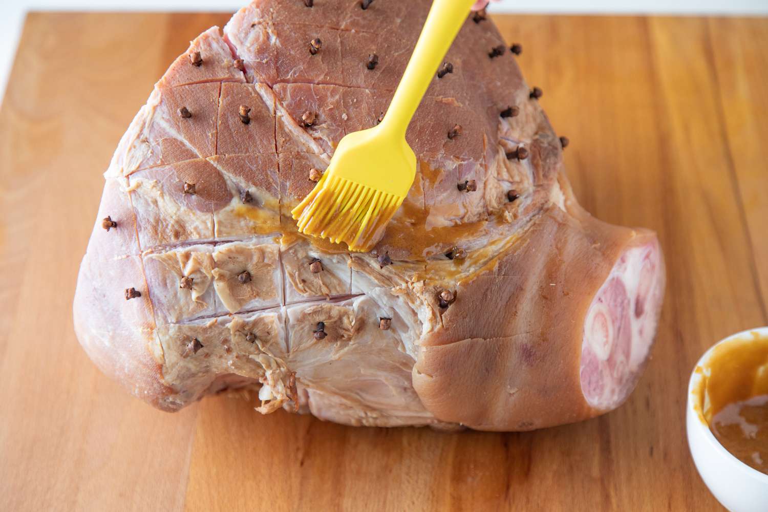 Spreading a glaze on a baked ham.