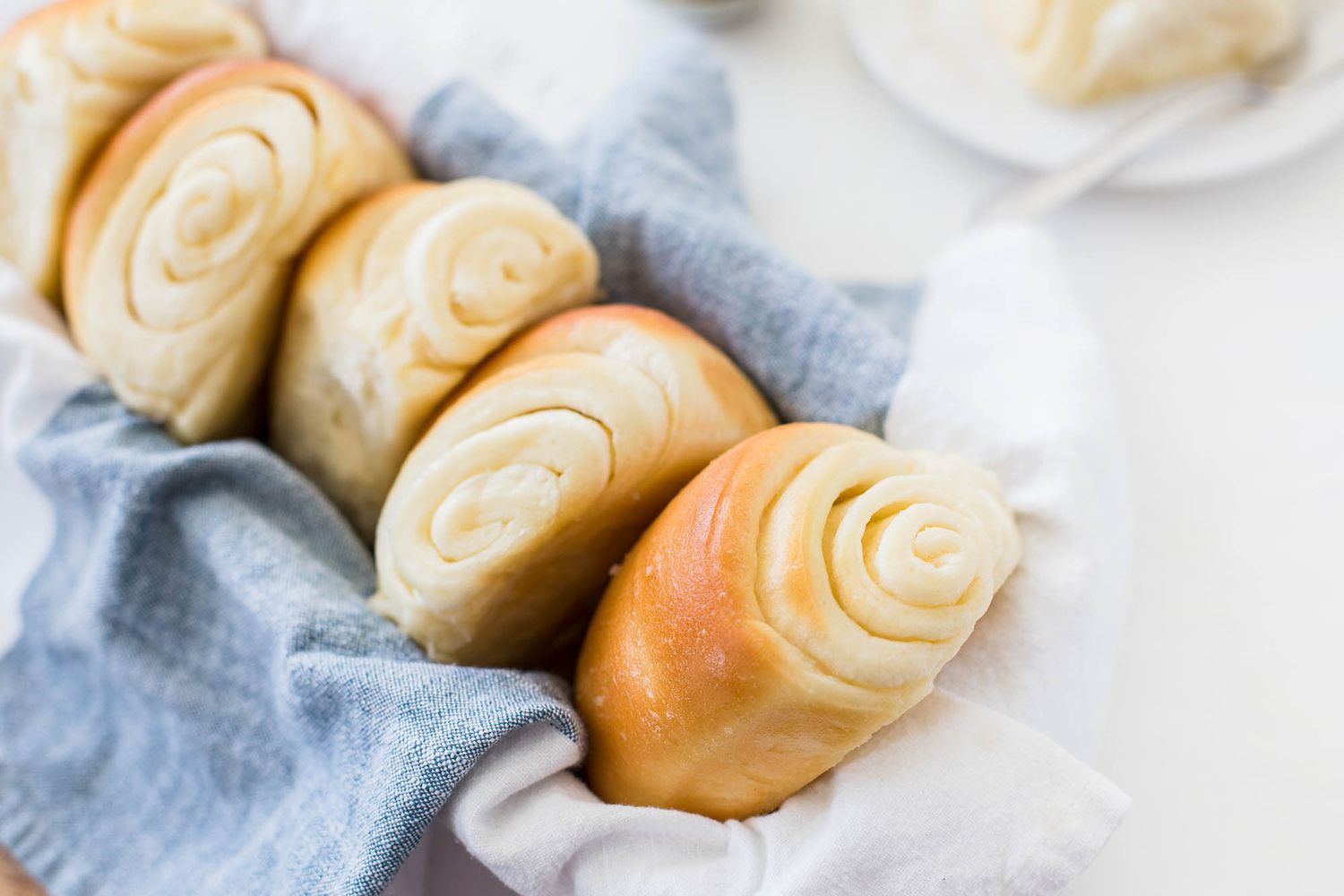 Four lion house dinner rolls in a basket with blue linens.