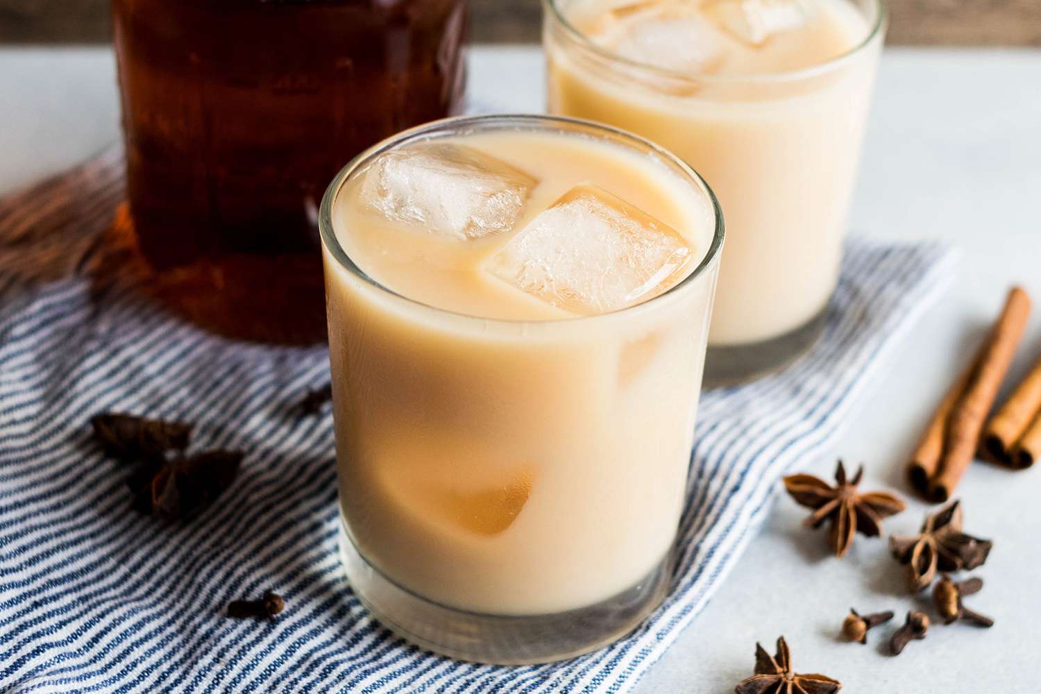 two glasses of iced chai with ice cubes on a counter