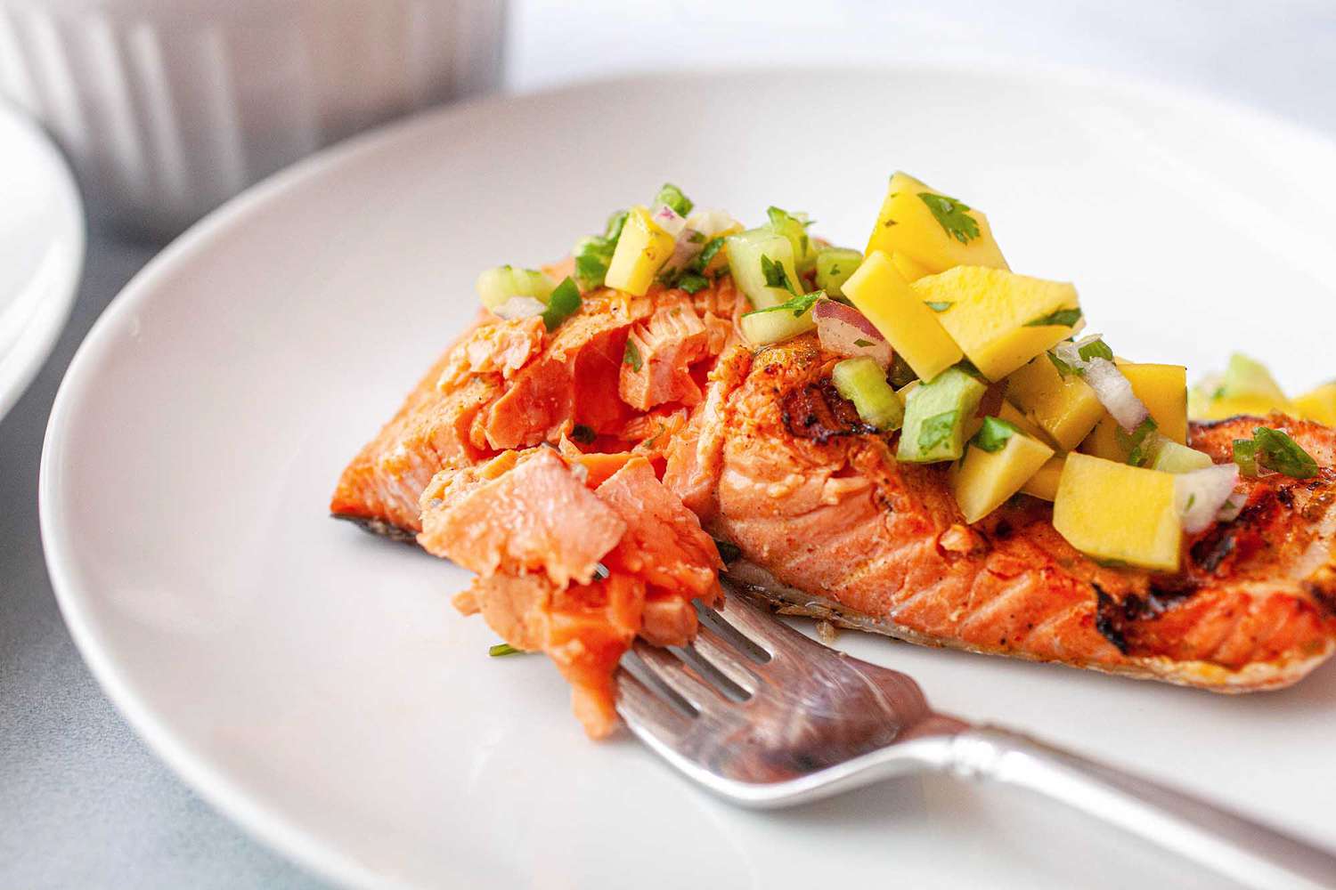 Grilled salmon on a plate topped with a mango salsa