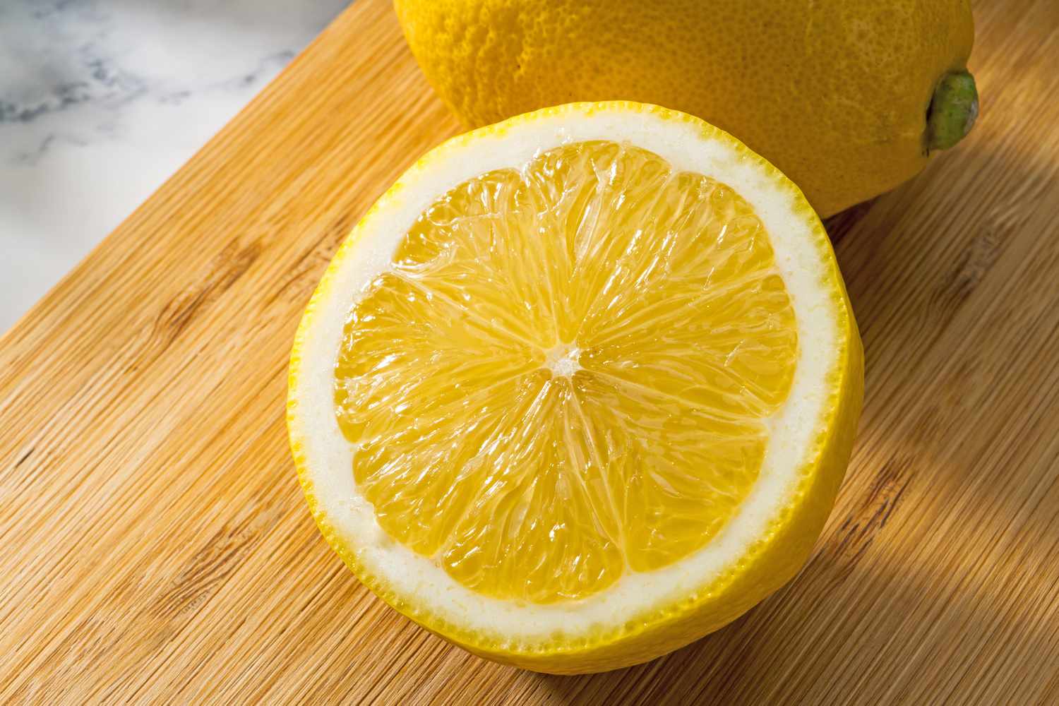 A halved lemon on a wooden cutting board