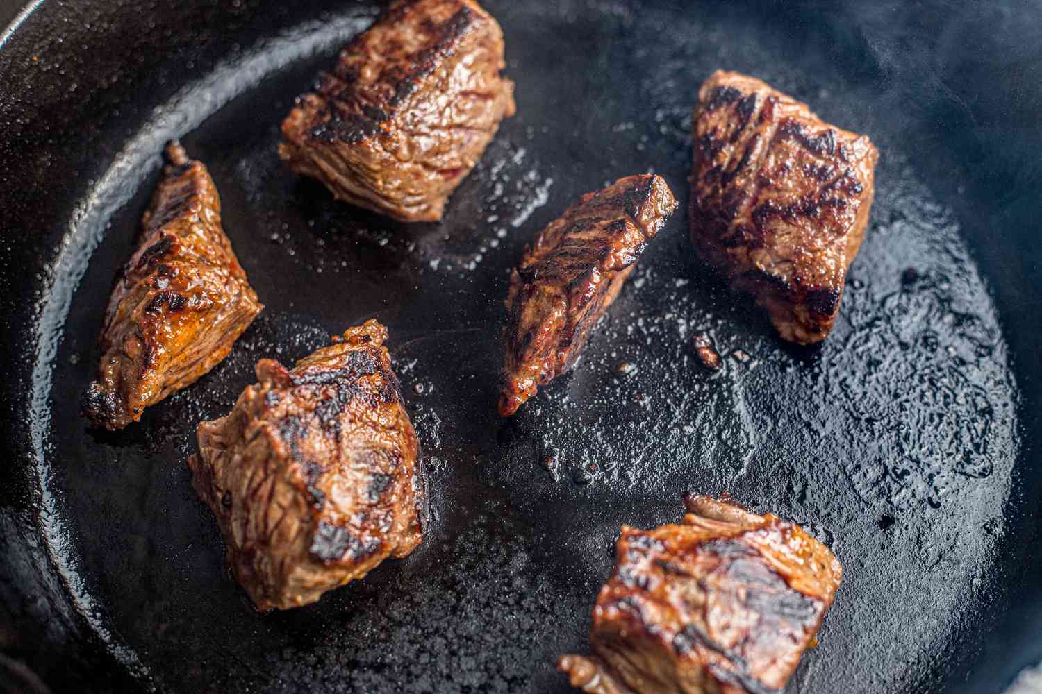 Steak tips flipped on the skillet to cook the other side of the steak