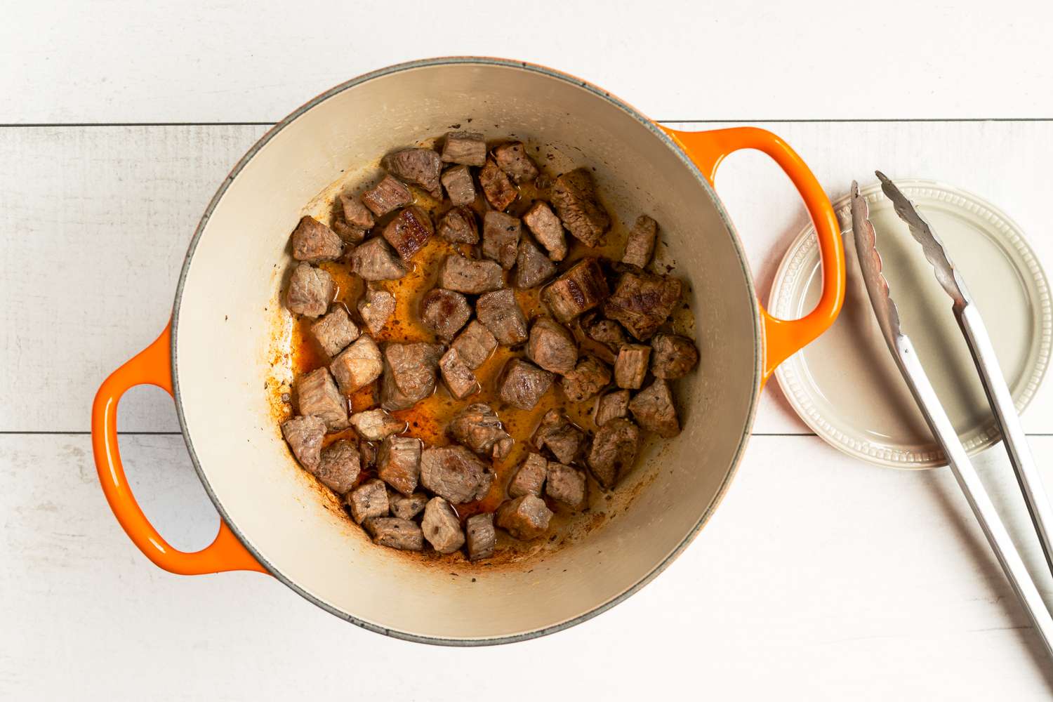 Cubed meat being browned in a pot prepared for a recipe