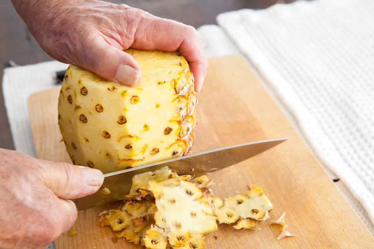 cut off the outer skin of the pineapple all the way around