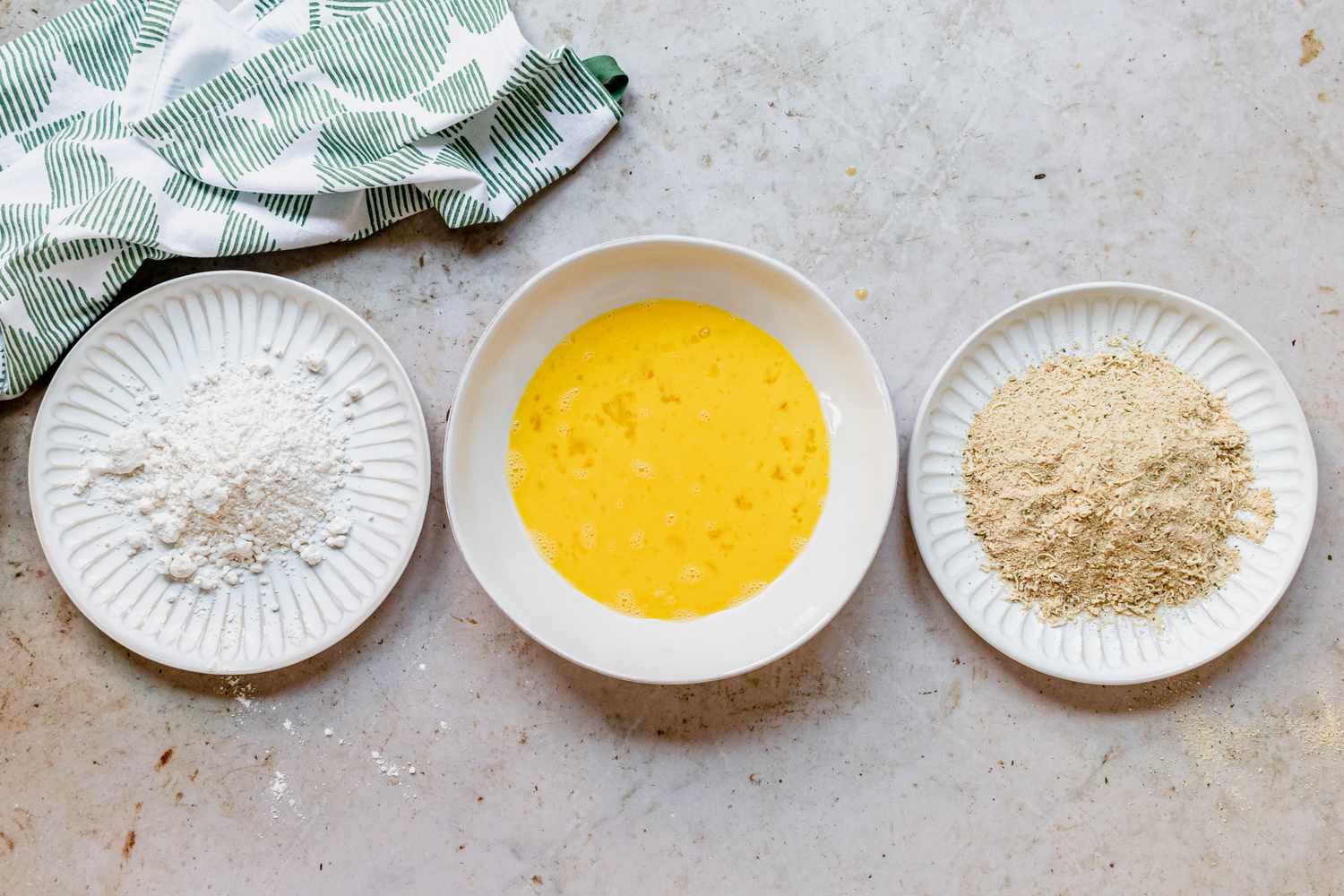 Breading station with a flour plate, egg wash plate, and breading plate lined up 