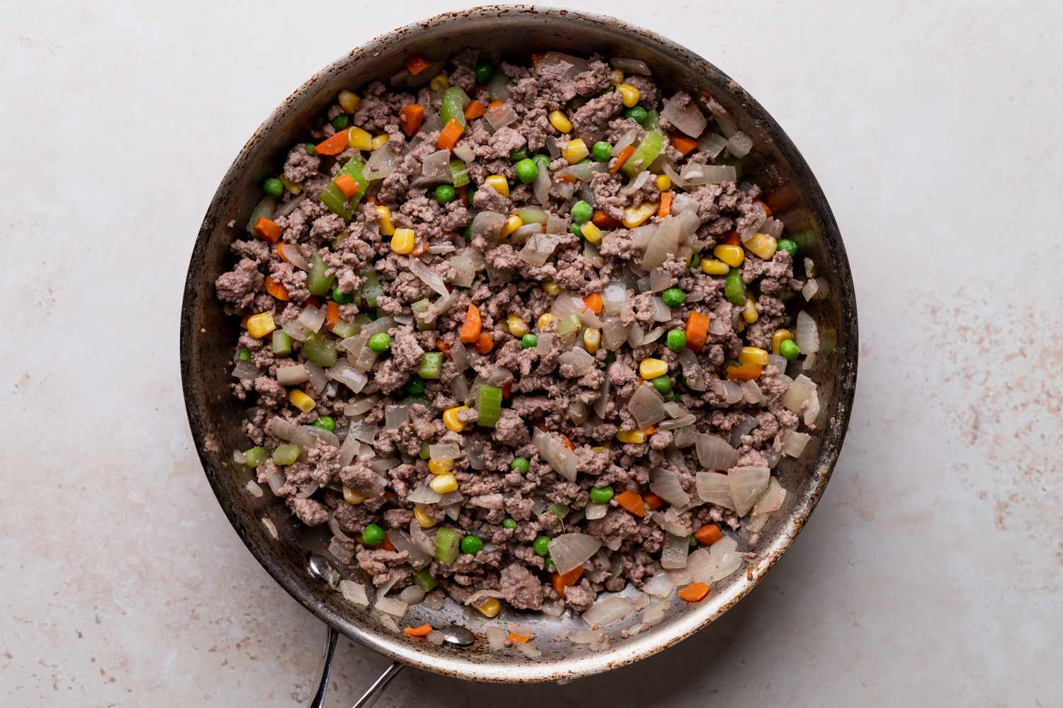 Ground beef and vegetables in a skillet to make the filling for a shepherds pie recipe.