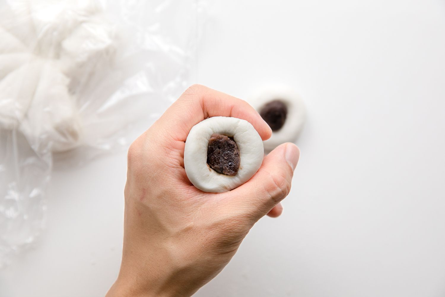 Filling the Tangyuan: Indented Dough Ball Placed on One Hand (Between the Index Finger and Thumb) and Indent Is Filled with Red Bean Paste 