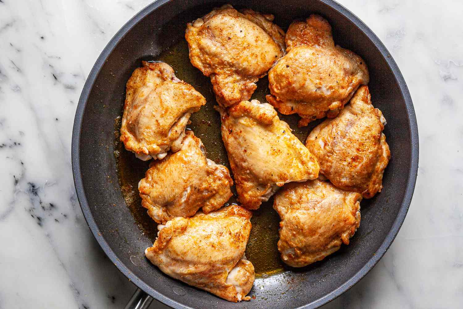 Pan fried chicken thighs in a skillet to show how to make smothered chicken thighs in onion gravy