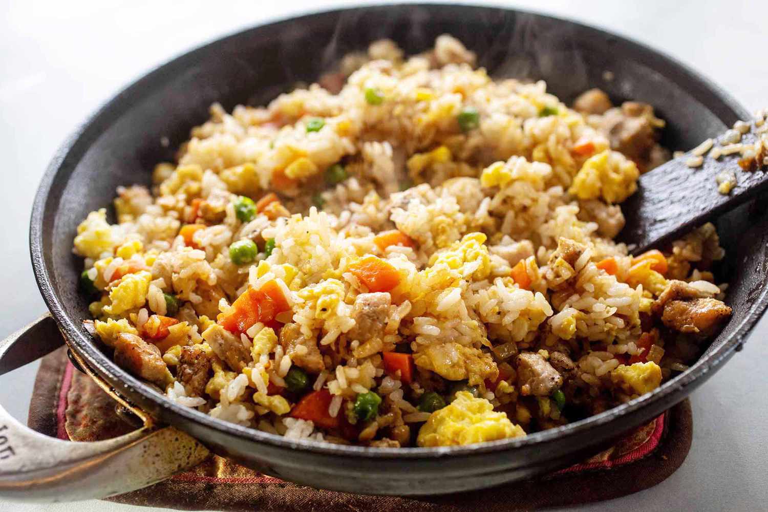 A skillet with cooking pork fried rice