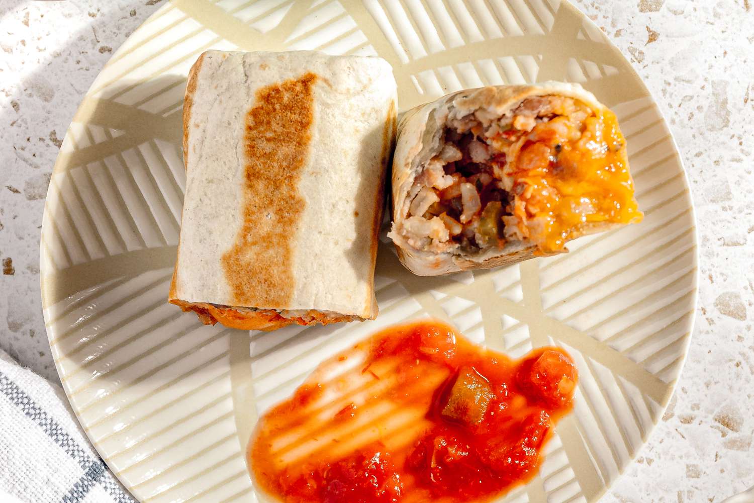 Easy Rice and Beans Freezer Burrito Cut in Half on a Plate and Served With Salsa