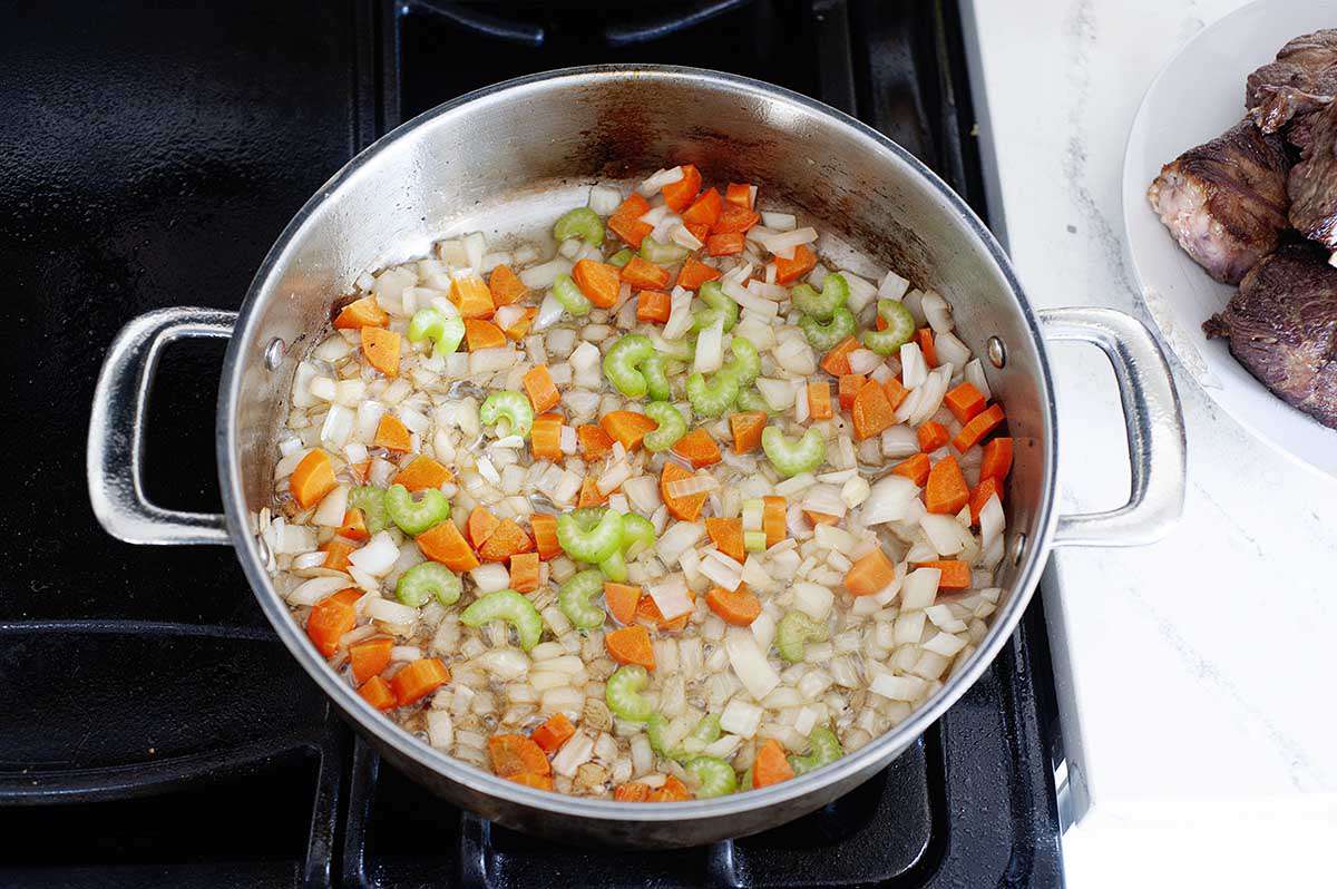 Vegetables sautéing in a pan for a beef short ribs recipe.