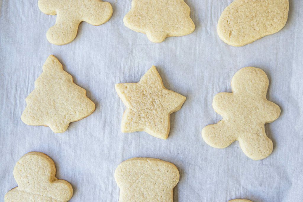 Christmas cookies cut into shapes and set on a parchment lined baking sheet.