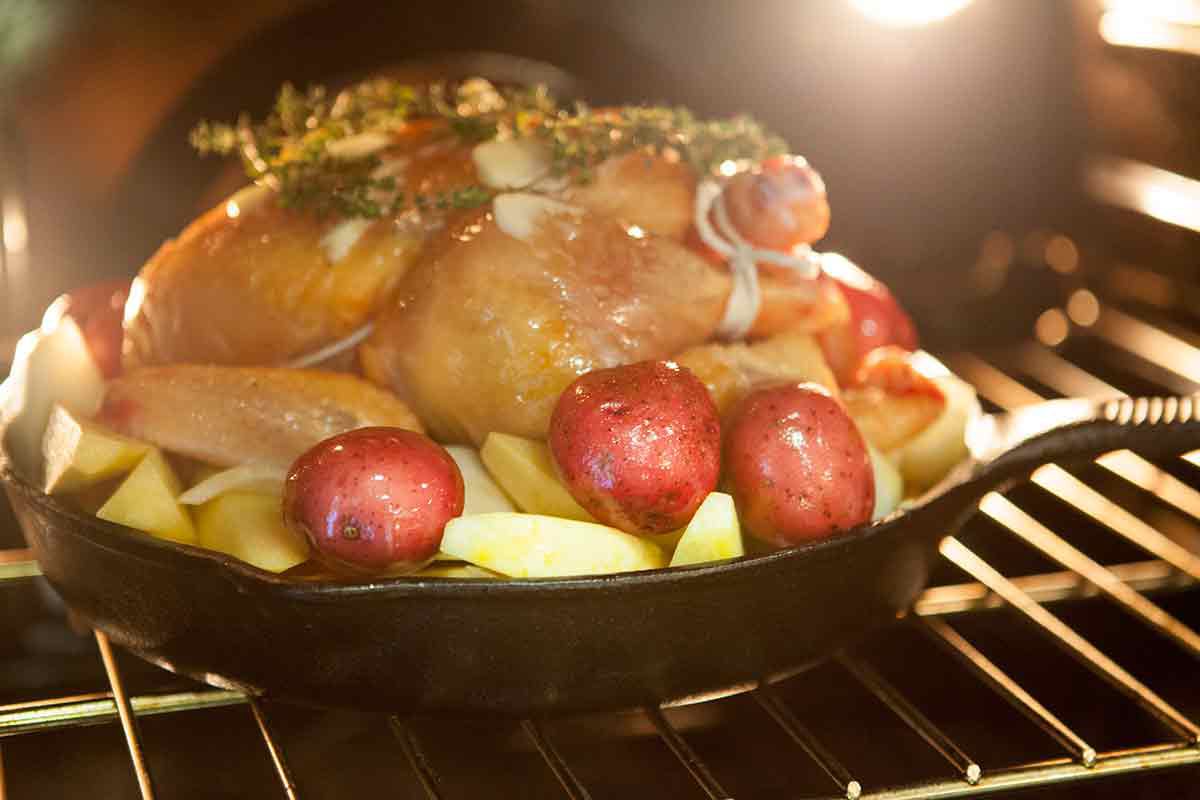 Cast iron roast chicken with vegetables in oven