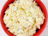 Overhead shot of a red bowl of creamy looking potato salad