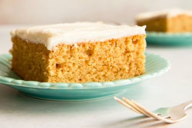 A slice of cake with icing on a plate with a fork nearby