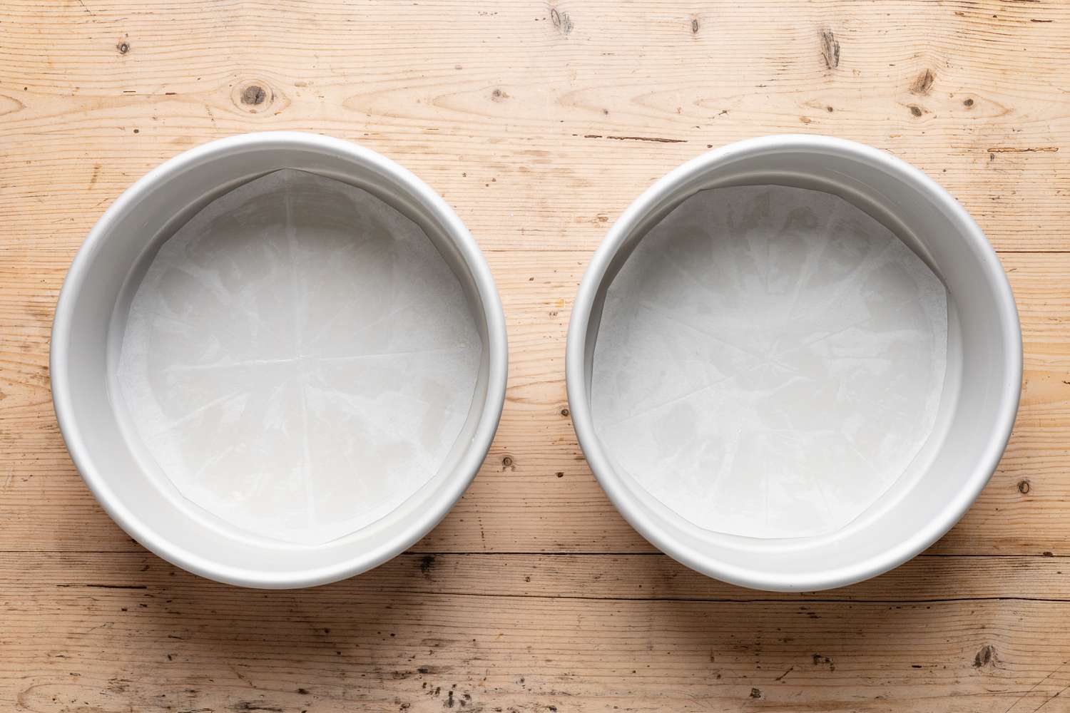 two round cake pans lined with parchment paper for strawberry cake recipe