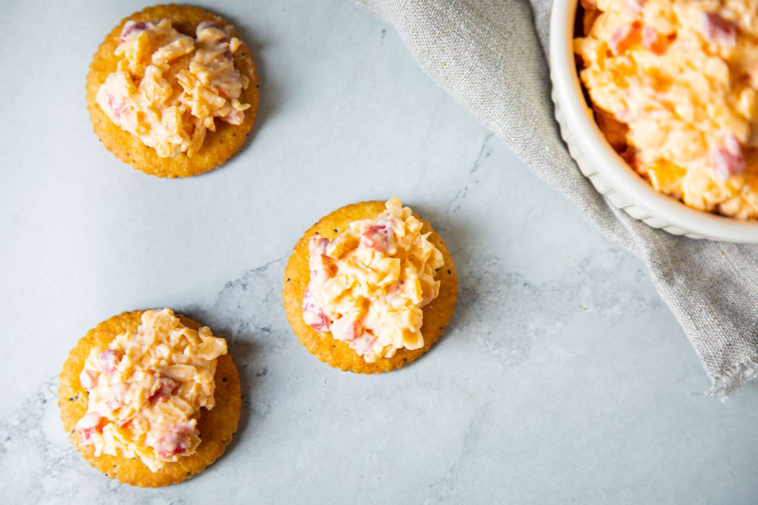 Pimento Cheese on Crackers with a Bowl in the Background