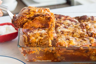 Cheesy chicken enchilada casserole, with a serving being lifted from the dish