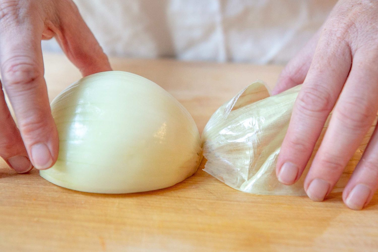 Halved Onion Placed on the Cutting Board With the Onion Peel Still Attached at the Root End for How To Chop an Onion