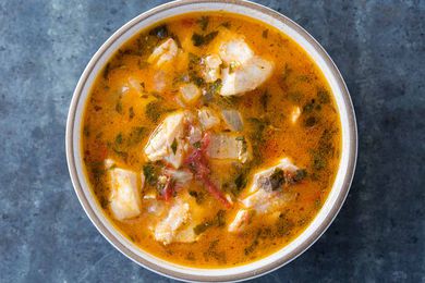 Fish stew in a white bowl on a gray table 