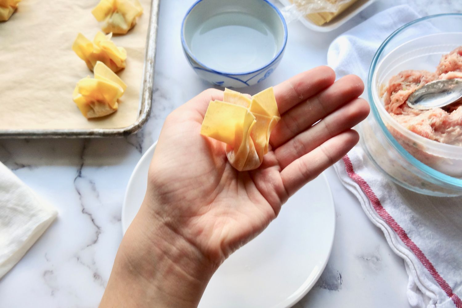 A finished wonton in a hand for a pork and ginger wontons in chicken soup