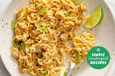 Plate of noodles garnished with green onions and a lime wedge fork resting on the plate