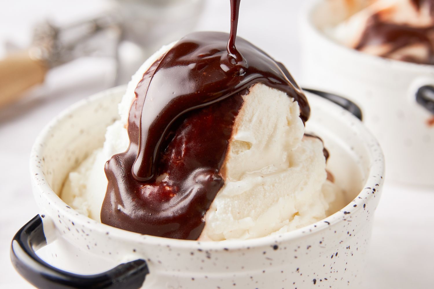 Hot fudge sauce poured onto vanilla ice cream in a bowl 