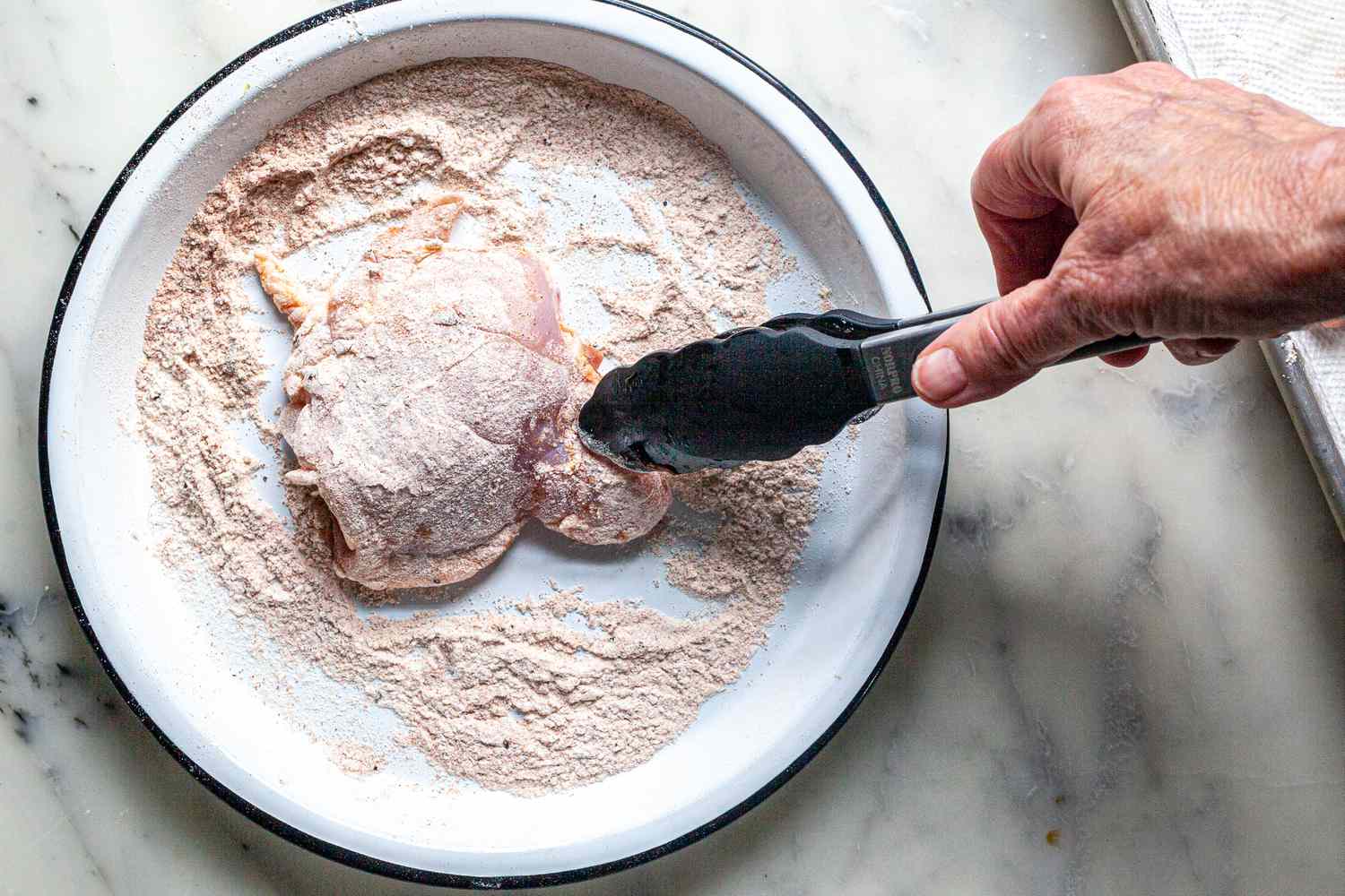 Coating chicken in seasoned flour mixture to make an easy smothered chicken and gravy recipe.