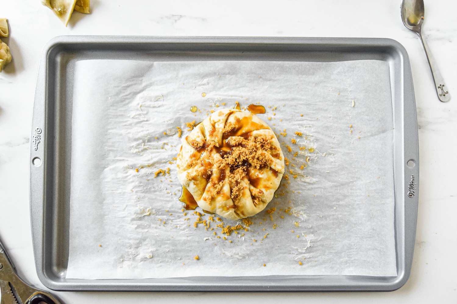 Overhead view of a baking sheet with brie wrapped in puff pastry for a baked brie recipe.
