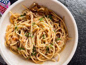 A white bowl with caramelized cabbage spaghetti, garnished with chopped parsley