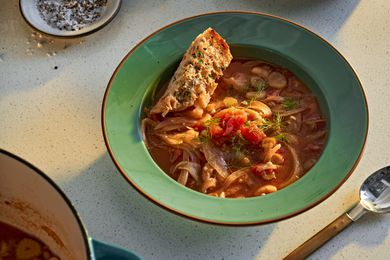 A bowl of tomato, white bean, and fennel stew on a kitchen counter