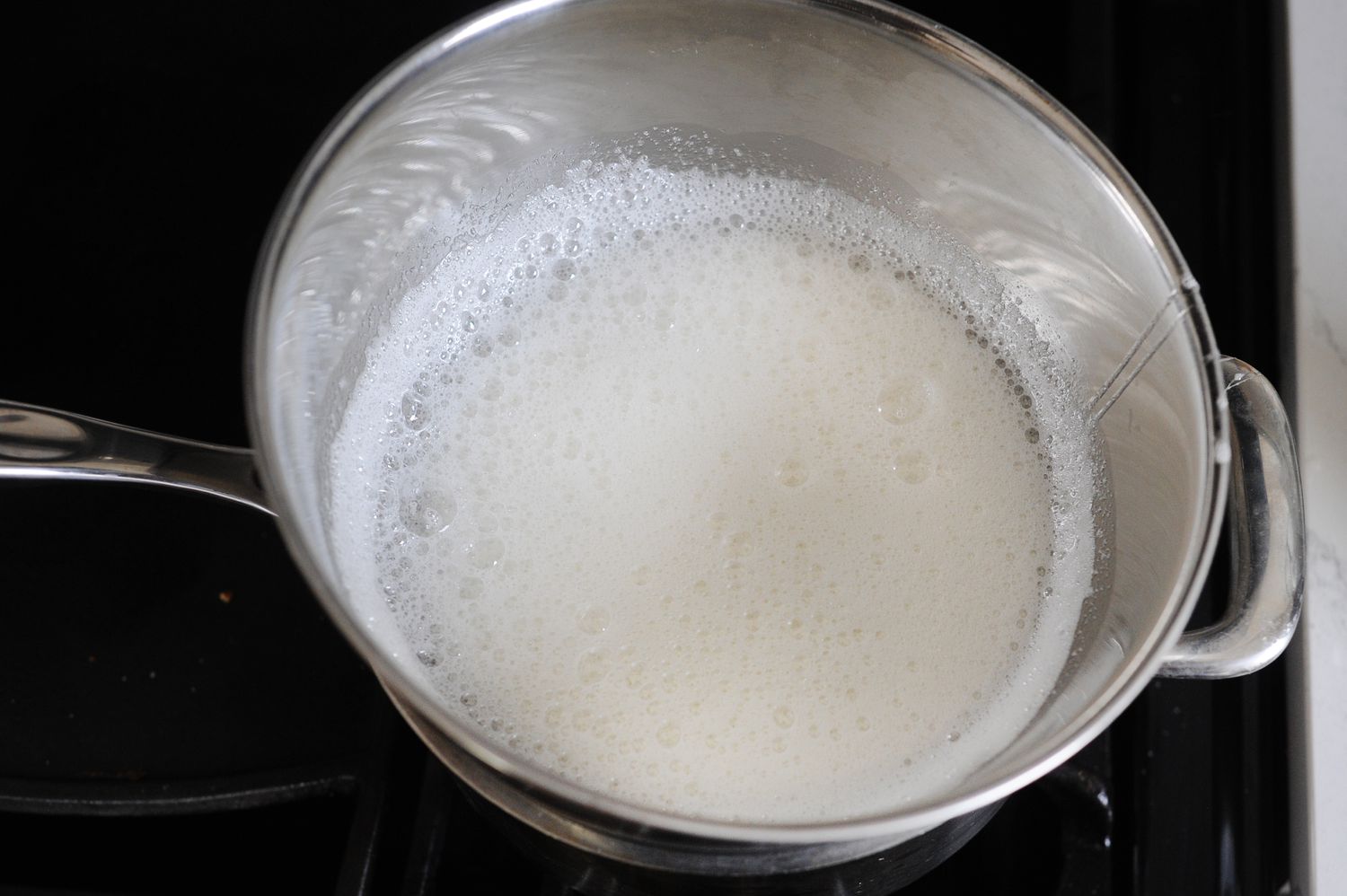 Frothy egg whites in a bowl to make No Fail Seven-Minute Frosting.