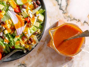 overhead view of a plate of salad with Chipotle Honey Vinaigrette in a small sauce pitcher with a spoon in it
