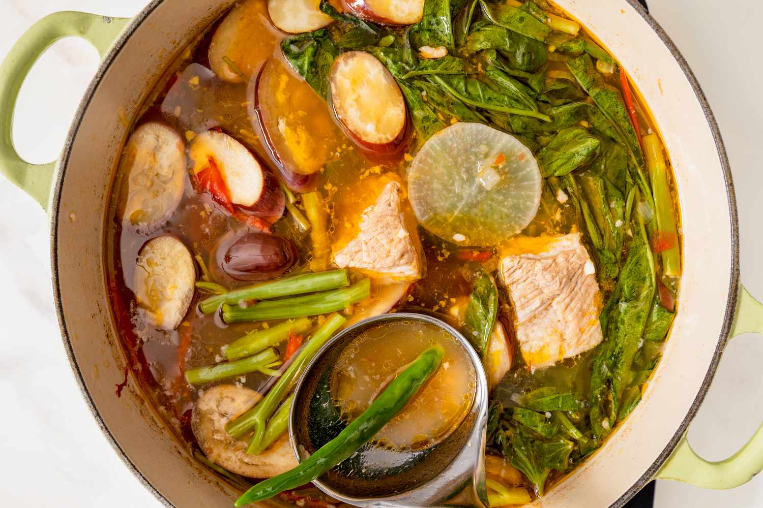 A pot of pork sinigang with vegetables and broth