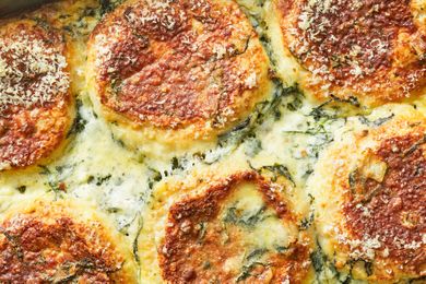 Closeup of a baked breakfast casserole with a cheese crust and visible ingredients like spinach and toasted toppings