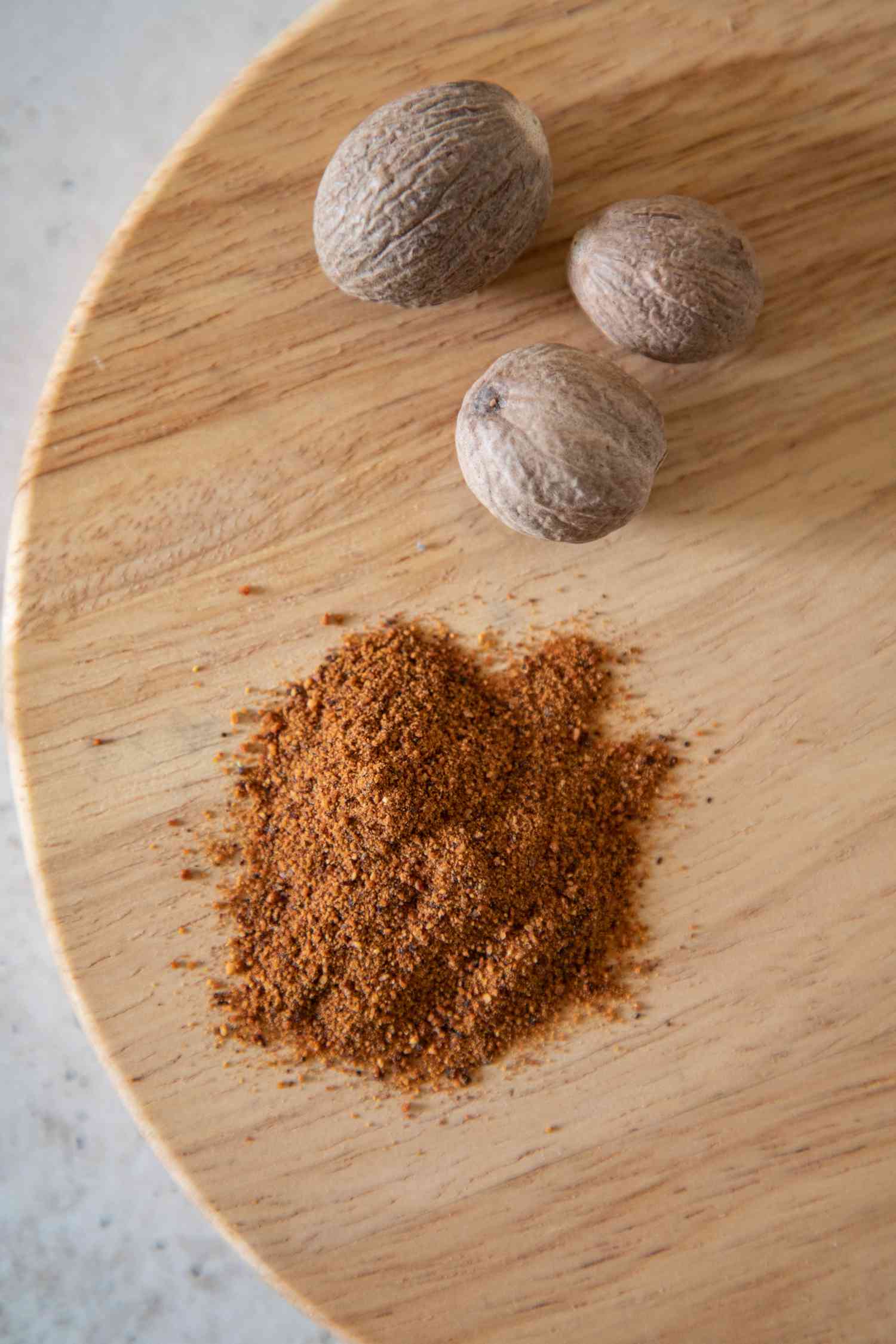 Whole and ground nutmeg on a wood serving platter