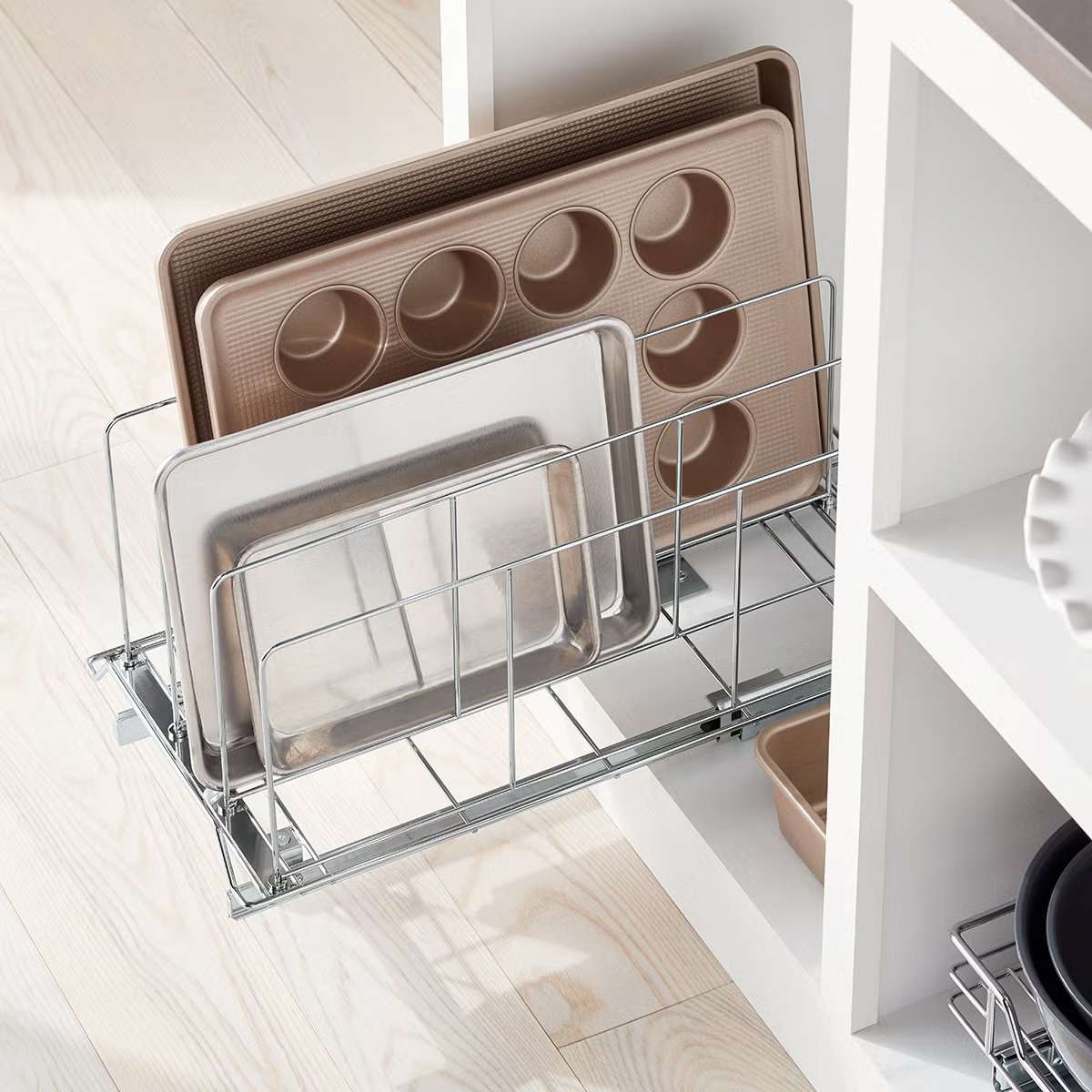 Organized baking trays and baking pans in a metal pullout rack installed in a kitchen cabinet
