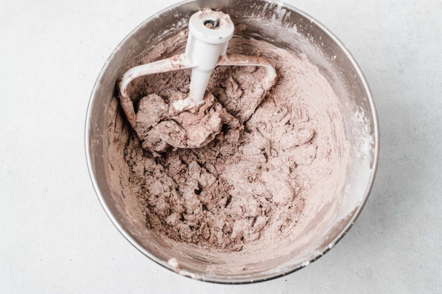 Adding dry ingredients to a bowl to make dough for holiday chocolate and peppermint shortbread.