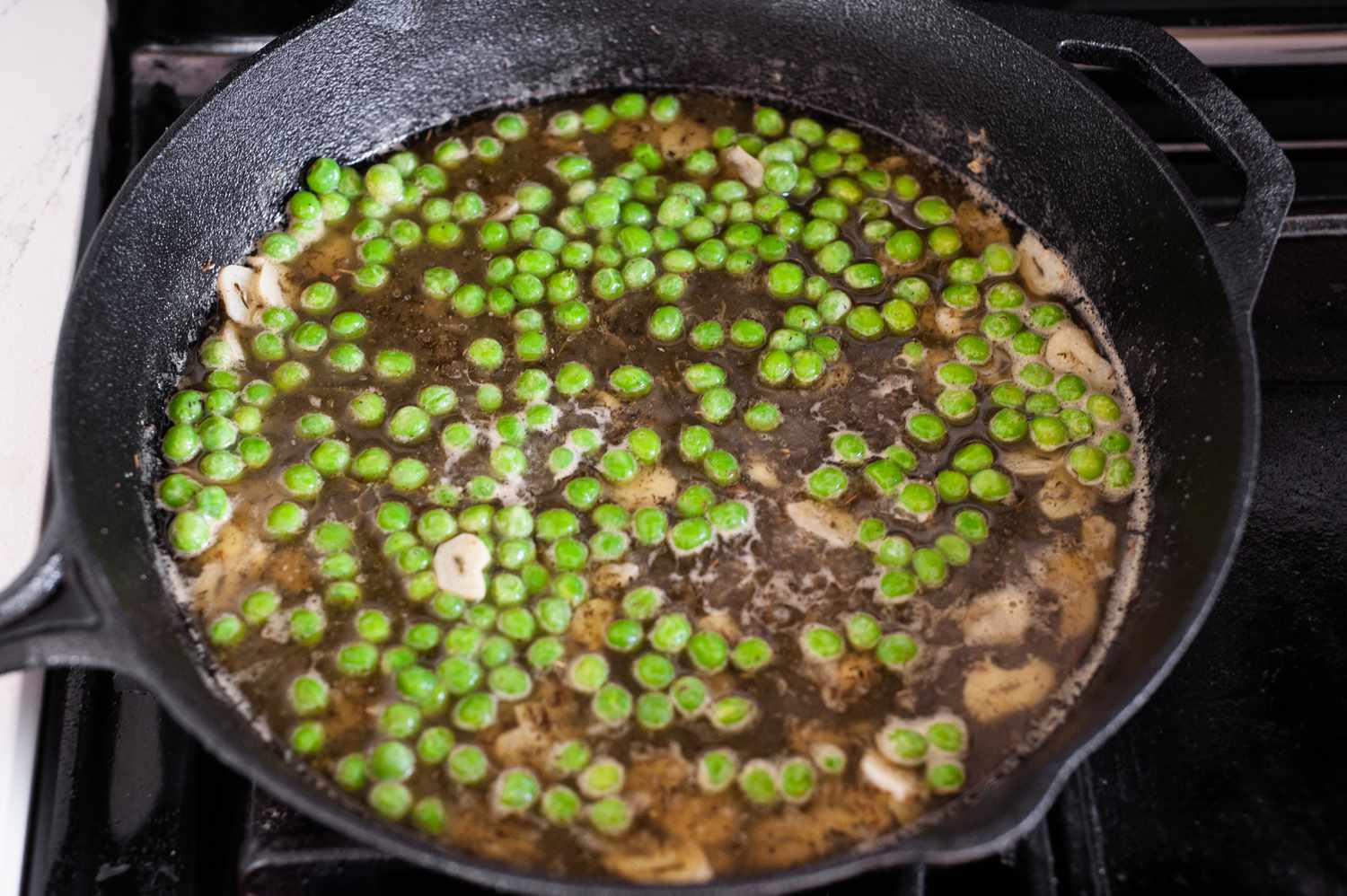 Garlic and Frozen Peas Cooking in Wine Sauce for Chicken Vesuvio