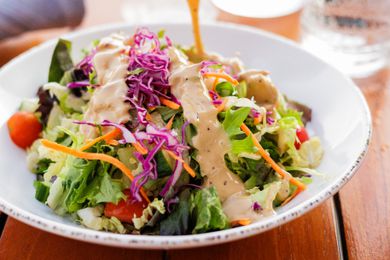 Close up of a salad with dressing being poured on it