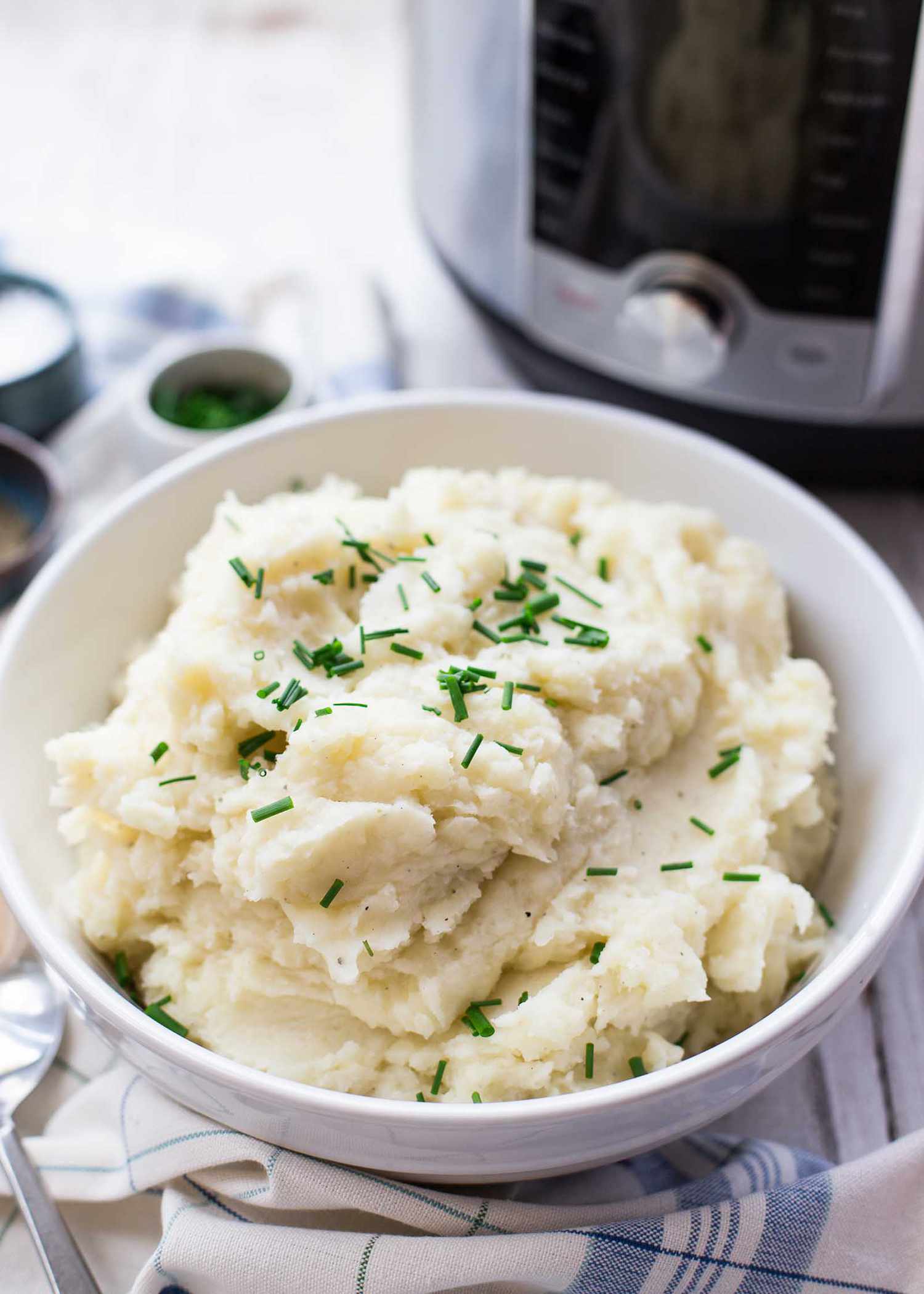 Bowl of pressure cooker mashed potatoes with an instant pot in the background