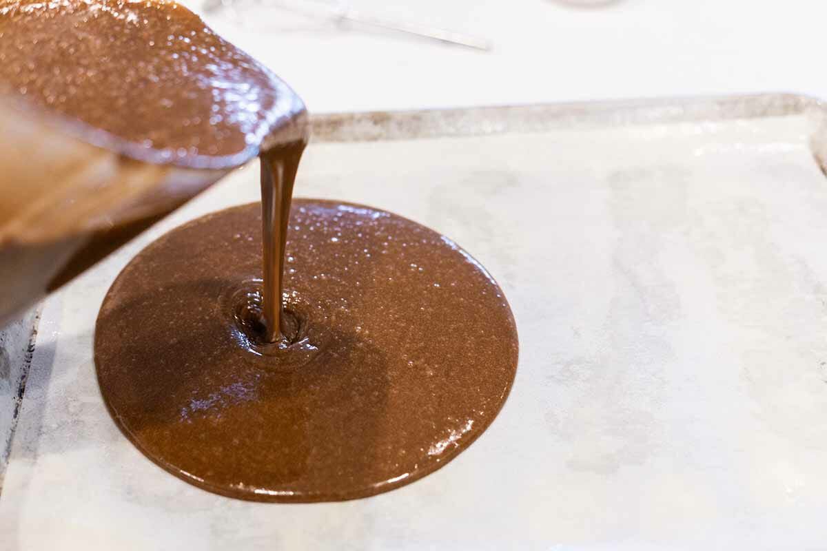 Pouring texas chocolate sheet cake into a sheet pan.