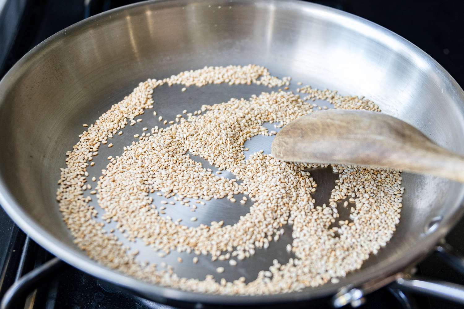 Raw Sesame Seeds on a Skillet Mixed Using a Spoon